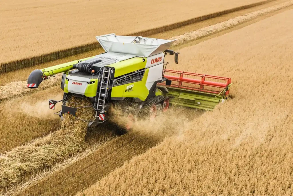 Nowoczesny kombajn marki Claas na gąsienicach pracujący na polu zboża podczas żniw